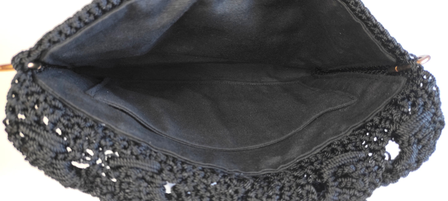 Bolso negro de fiesta estilo bandolera con aplique decorativo de pedrería acrílica en forma floral.