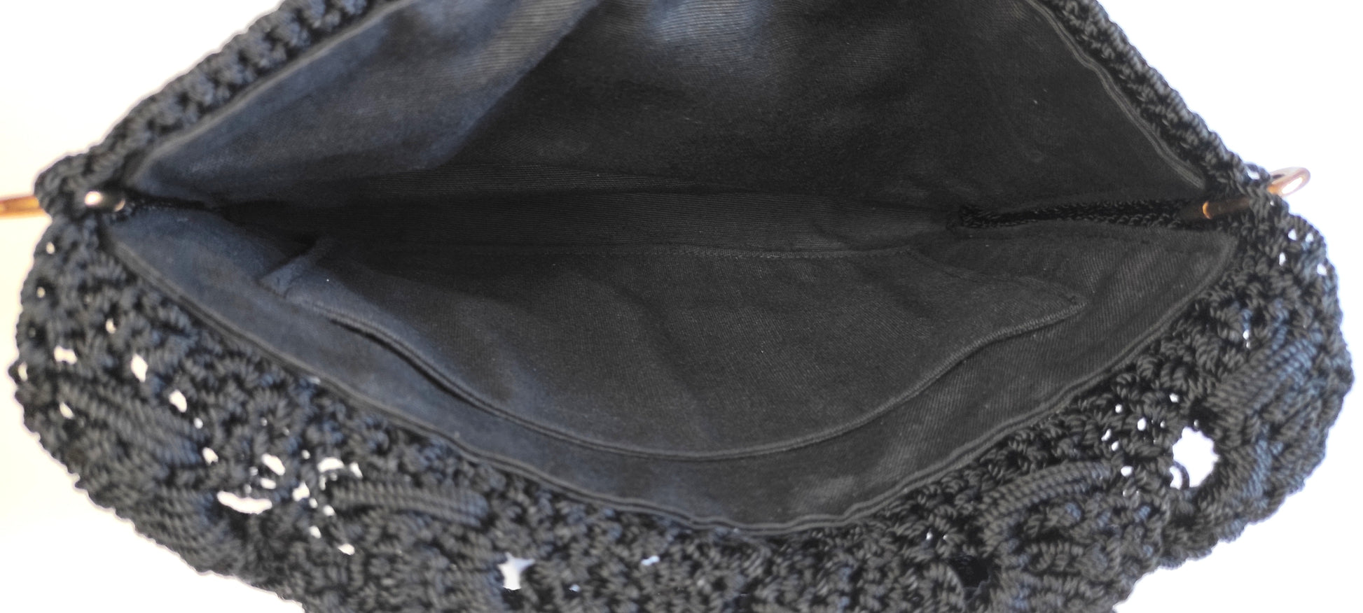 Bolso negro de fiesta estilo bandolera con aplique decorativo de pedrería acrílica en forma floral.